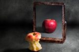 apple with anorexia looking at its reflection in a mirror