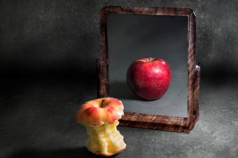 apple with anorexia looking at its reflection in a mirror