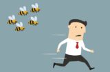Businessman running away from angry bees