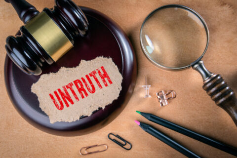 UNTRUTH. Law, regulations and judgment concept. Judge's hammer, stationery and magnifying glass