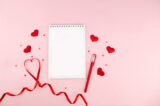 Notebook with red heart shape decorations and red ribbon on pink background. Wedding, Romantic and Happy Valentine day holiday concept.