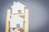 Model Houses On Rungs Of Wooden Property Ladder
