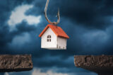 A toy house on a hook hanging over a precipice. Debt concept