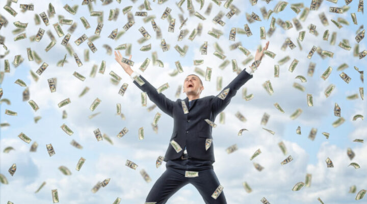 Happy businessman in celebrating pose with loads of money in