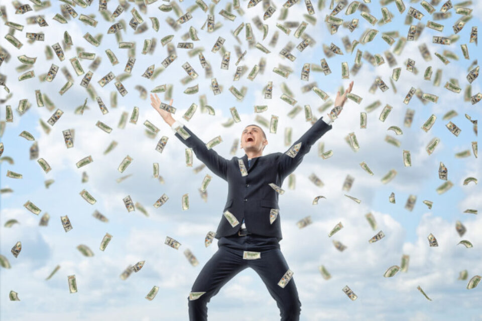 Happy businessman in celebrating pose with loads of money in