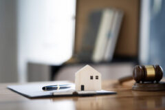 Wooden house model with clip board and wooden gavel  put together on tablet for background, real estate and justice concept.