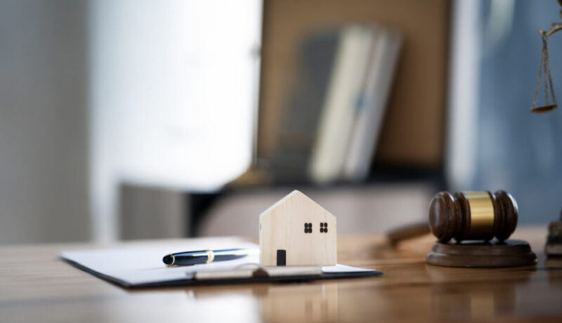 Wooden house model with clip board and wooden gavel  put together on tablet for background, real estate and justice concept.